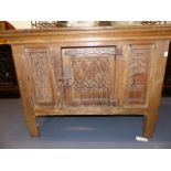 A 17th.C.OAK LOW CUPBOARD WITH GOTHIC CARVED PANELS AND IRON STRAP HINGES. W.104cms.