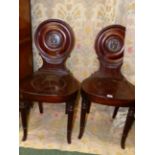 A PAIR OF CARVED MAHOGANY REGENCY HALL CHAIRS IN THE GILLOWS MANNER, CIRCULAR BACKS PAINTED WITH