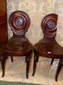 A PAIR OF CARVED MAHOGANY REGENCY HALL CHAIRS IN THE GILLOWS MANNER, CIRCULAR BACKS PAINTED WITH