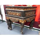 A CHINESE GILT AND EBONISED CARVED ALTAR TABLE WITH SHAPED TOP ABOVE PANELLED FRIEZE SCROLL LEGS.