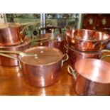 A POLISHED COPPER AND BRASS ANTIQUE AND LATER PART BATTERIE DE CUISINE TO INCLUDE FOUR LARGE COVERED