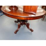 A CARVED MAHOGANY VICTORIAN CIRCULAR TILT TOP TABLE WITH FOLIATE DECORATED PEDESTAL AND FOUR