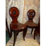 A PAIR OF REGENCY CARVED MAHOGANY SABRE LEG HALL CHAIRS, CIRCULAR BACKS WITH PAINTED ARMORIAL