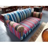 A VINTAGE THREE SEAT SETTEE COVERED IN STRIPED FABRIC ON BUN FEET WITH BRASS CASTORS. W.180cms.