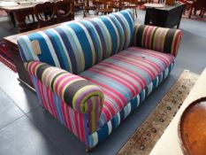 A VINTAGE THREE SEAT SETTEE COVERED IN STRIPED FABRIC ON BUN FEET WITH BRASS CASTORS. W.180cms.