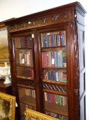 AN ANTIQUE FRENCH CARVED WALNUT BOOKCASE WITH GRILL PANEL DOORS ENCLOSING SHELVES, FOLIATE PILASTERS