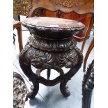 AN ORIENTAL CARVED HARDWOOD STAND OF CIRCULAR FORM WITH FLOWERHEAD DECORATED APRON. H.56cms.