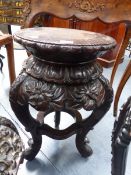 AN ORIENTAL CARVED HARDWOOD STAND OF CIRCULAR FORM WITH FLOWERHEAD DECORATED APRON. H.56cms.