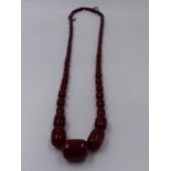 A GRADUATED CYLINDRICAL ROW OF CHERRY AMBER BEADS, APPROXIMATE LENGTH 92cms, APPROXIMATE