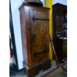 AN ARTS AND CRAFTS ELM HALL CABINET WITH WROUGHT IRON HINGES TO SINGLE PLANK DOOR ENCLOSING SHELVES.