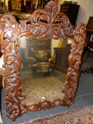 AN ELABORATELY CARVED FRAME MIRROR WITH SCROLLED PIERCED BRANCH FORM DECORATION WITH CLUSTERS OF