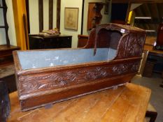 AN ANTIQUE CARVED OAK CHILD'S CRADLE CONVERTED AS A PLANTER.
