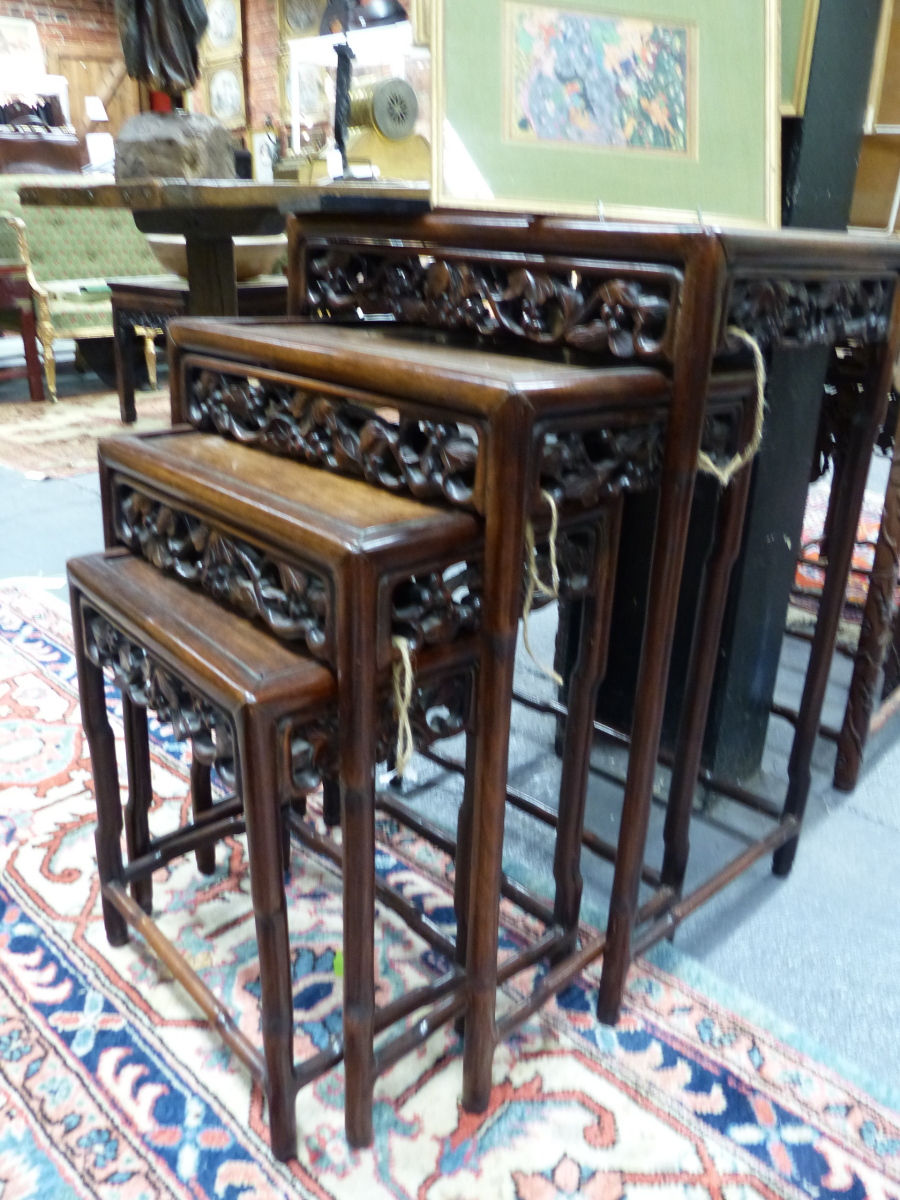 A NEST OF FOUR CHINESE CARVED HARDWOOD TABLES WITH PIERCED FOLIATE APRONS.