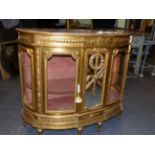 A FRENCH CARVED GILTWOOD BOW FRONT MARBLE TOP DISPLAY CABINET THE CENTRAL MIRROR PANEL DECORATED