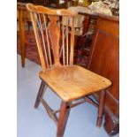 AN EARLY COUNTRY ELM SEAT SIDE CHAIR WITH SPINDLE BACK AND SHAPED CREST RAIL.