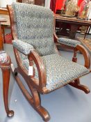 A CARVED MAHOGANY LATE VICTORIAN ROCKING CHAIR WITH REEDED FRAME AND SPINDLE SUPPORTS.