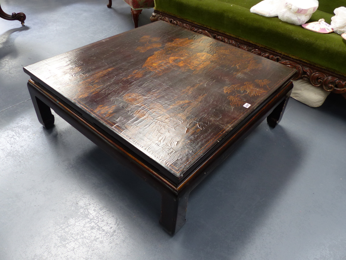 AN ORIENTAL GILT AND EBONISED SQUARE LOW TABLE WITH LANDSCAPE DECORATION TO THE TOP. H.38 W.101cms.