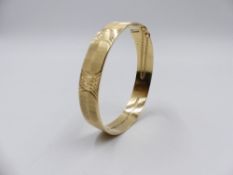 A 9ct YELLOW GOLD HALLMARKED BANGLE WITH A DIAMOND CUT AND SATIN FINISH COMPLETE WITH SAFETY