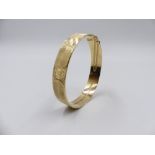 A 9ct YELLOW GOLD HALLMARKED BANGLE WITH A DIAMOND CUT AND SATIN FINISH COMPLETE WITH SAFETY