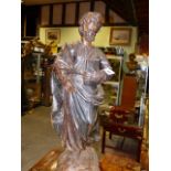 AN EARLY CARVED FIGURE OF A STANDING SAINT HOLDING A BOOK MOUNTED ON AN ANTIQUE TIMBER SECTION.