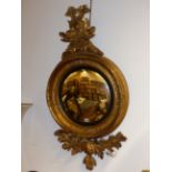 A LARGE REGENCY CARVED GILTWOOD CONVEX MIRROR WITH ENTWINED DOLPHIN CREST. H.128cms.