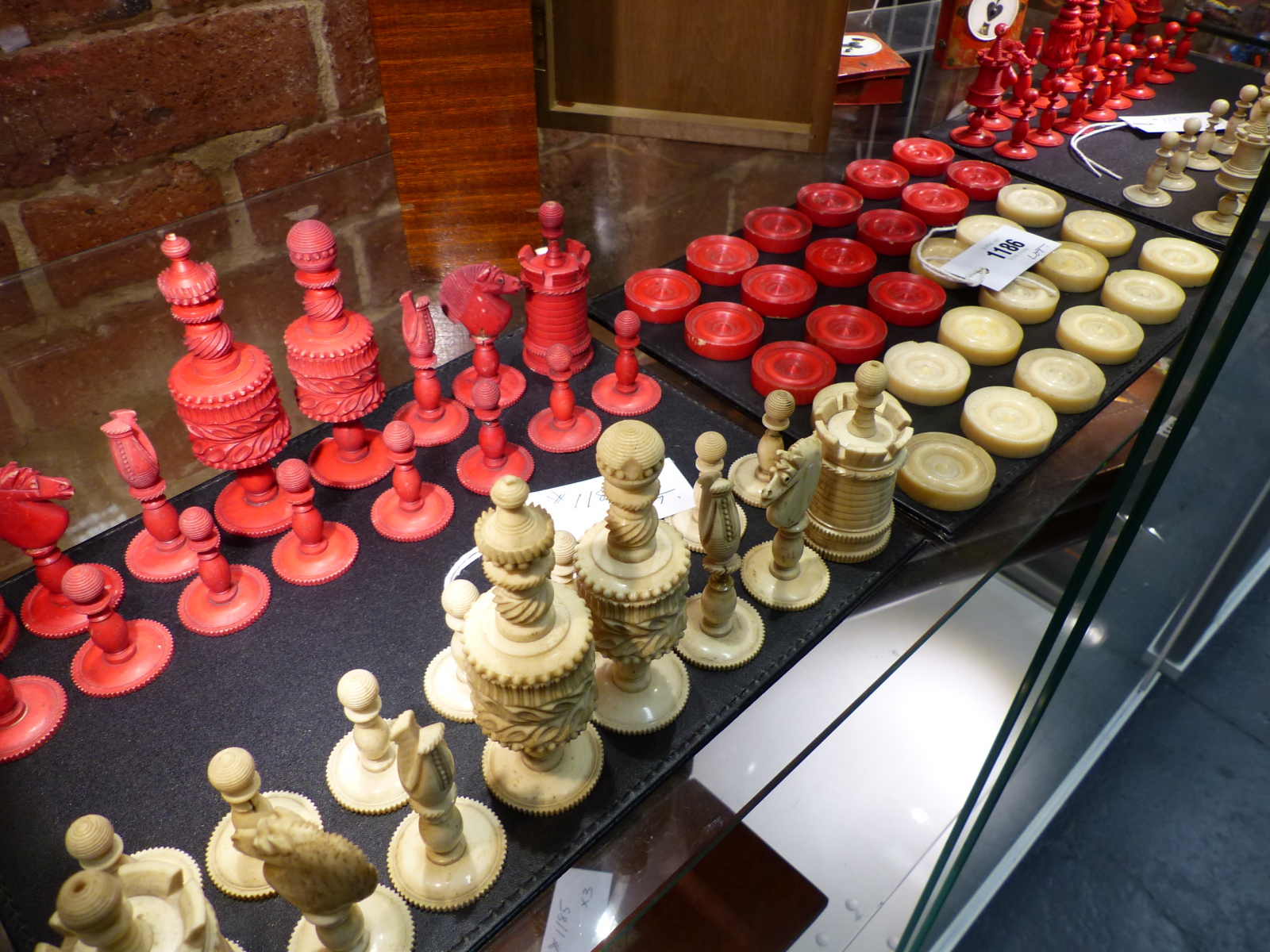 THREE ANTIQUE CARVED AND STAINED IVORY AND BONE BOARD GAME PIECES, TWO CHESS SETS AND A SET OF