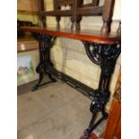 AN ANTIQUE CAST IRON BASED TABLE WITH MAHOGANY TOP.