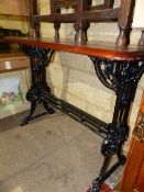 AN ANTIQUE CAST IRON BASED TABLE WITH MAHOGANY TOP.