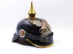 A GERMAN PICKLEHAUBE HELMET WITH BLACK LEATHER SKULL AND SPIKE FINIAL AND WINGED GRIFFIN HELMET