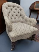 A VICTORIAN UPHOLSTERED BUTTON BACK ARMCHAIR ON RING TURNED FRONT LEGS ENDING IN CERAMIC CASTORS.