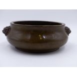 A HEAVY CHINESE BRONZE CENSER WITH MASK HANDLES AND IMPRESSED MARKS TO BASE. D.16cms