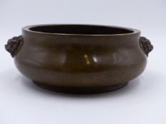 A HEAVY CHINESE BRONZE CENSER WITH MASK HANDLES AND IMPRESSED MARKS TO BASE. D.16cms