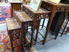 A NEST OF FOUR CHINESE CARVED HARDWOOD TABLES WITH PIERCED FOLIATE APRONS.