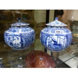 A NEAR PAIR OF CHINESE BLUE AND WHITE COVERED JARS WITH FIGURAL PANELS SURROUNDED BY SCROLLING