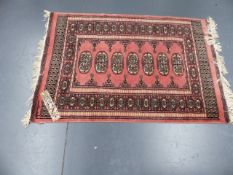 AN ORIENTAL RUG OF BOKHARA DESIGN AND THREE SMALL TRIBAL MATS.