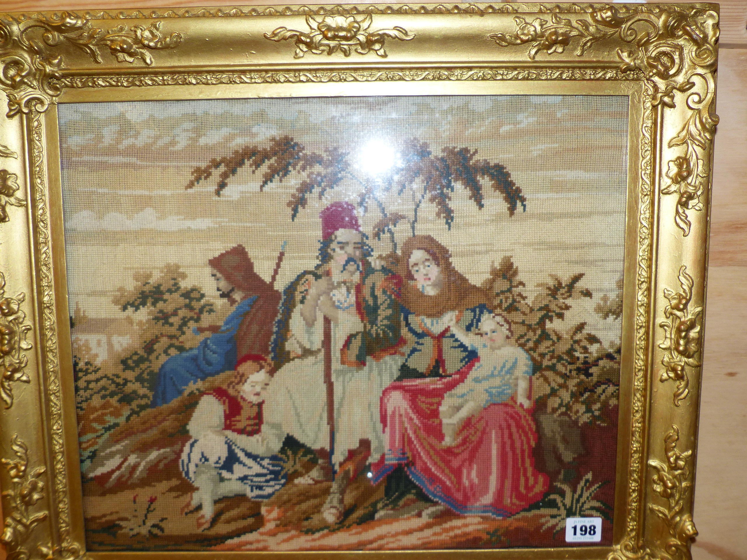 A VICTORIAN NEEDLEPOINT PANEL OF AN EASTERN FAMILY IN GILT FRAME. OVERALL 54 x 62cms.