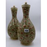 A PAIR OF EASTERN POTTERY BOTTLE FORM COVERED VASES WITH OVERALL FLORAL AND FOLIATE DECORATION. H.
