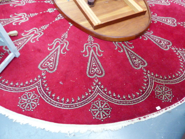 A LARGE CIRCULAR RED GROUND RUG.