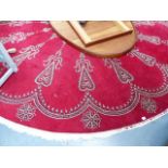 A LARGE CIRCULAR RED GROUND RUG.