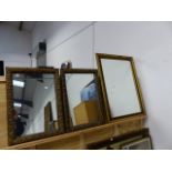 AN ARTS AND CRAFTS GILT FRAMED MIRROR AND A PAIR OF SMALLER GILT FRAMED MIRRORS.