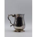 A GEORGIAN SILVER HALLMARKED PINT TANKARD HAVING A PLAIN ROUND BELLIED BODY SITTING ON A COLLET