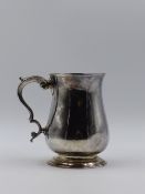 A GEORGIAN SILVER HALLMARKED PINT TANKARD HAVING A PLAIN ROUND BELLIED BODY SITTING ON A COLLET