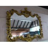 AN ANTIQUE CARVED GILTWOOD MIRROR IN THE CHIPPENDALE MANNER. W.110 x H.95cms.