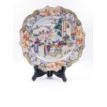 A CHINESE EXPORT FAMILLE ROSE PLATE WITH MANDARIN FIGURAL DECORATION AND LANDSCAPE PANELS TO THE