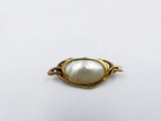 A MOTHER OF PEARL BROOCH SET IN PRECIOUS YELLOW METAL. APPROXIMATE WIDTH 3.5cms.