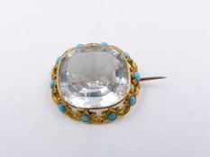 A ROCK CRYSTAL AND TURQUOISE BROOCH MOUNTED IN A PRECIOUS YELLOW METAL SCROLL WORK SETTING.