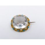 A ROCK CRYSTAL AND TURQUOISE BROOCH MOUNTED IN A PRECIOUS YELLOW METAL SCROLL WORK SETTING.