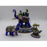 THREE INDIAN ENAMEL AND SILVERED FIGURES OF ELEPHANTS, TWO WITH HOWDAHS AND RIDERS. LARGEST H.16.