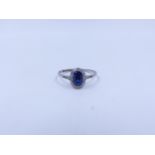 AN OVAL CUT SAPPHIRE AND DIAMOND HALO SET PLATINUM RING COMPLETE WITH DIAMOND SET SHOULDERS.