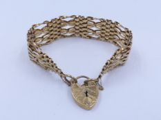 A 9ct GOLD SIX BAR GATE BRACELET COMPLETE WITH SAFETY CHAIN AND PADLOCK. APPROXIMATE WEIGHT 26grms.